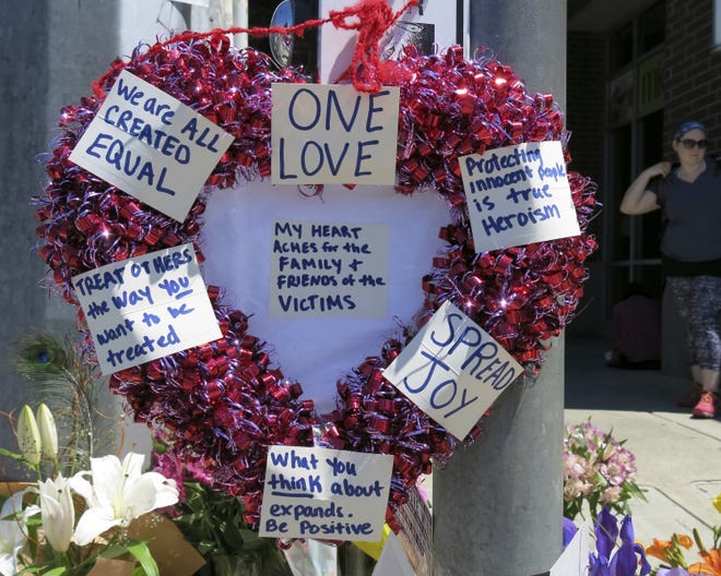 A heart-shaped wreath covered with positive messages hangs on a traffic light pole at a memorial for two bystanders who were stabbed to death Friday, while trying to stop a man who was yelling anti-Muslim slurs and acting aggressively toward two young women, including one wearing a Muslim head covering, on a light-trail train in Portland, Ore, Saturday, May 27, 2017. A memorial grew all day Saturday outside the transit center in Portland, as people stopped with flowers, candles, signs and painted rocks. Jeremy Joseph Christian, 35, was booked on suspicion of murder and attempted murder in the attack. (AP Photo/Gillian Flaccus)