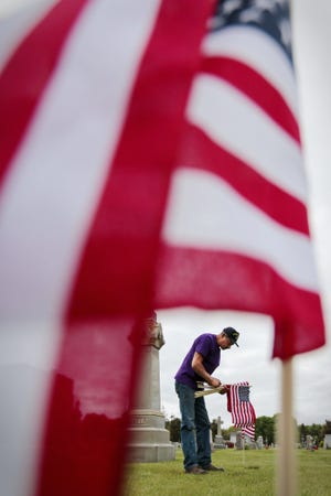 Danny DaSilva of the Cape Verdean American Veterans Association places American flags at the gravesites of veterans buried at St. John Cemetery on Allen Street in New Bedford in preparation for Memorial Day 2014. [PETER PEREIRA/HATHAWAY NEWS SERVICE FILE/SCMG]