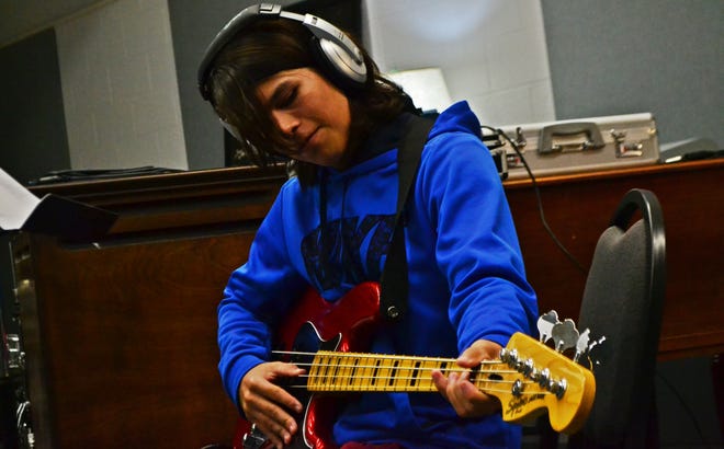 Aristotle Lawson, a seventh-grade University Academy student, warms up on the base guitar in the recording studio Tuesday at Gulf Coast State College. [ERYN DION/THE NEWS HERALD]