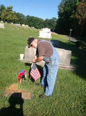 Tommy Hook, Jr. Legion member is shown placing a flag on the grave of his uncle, SGT Claude Eugene Elmore, killed in action in the Vietnam War. [PHOTO COURTESY OF BESSEMER CITY AMERICAN LEGION POST 243]