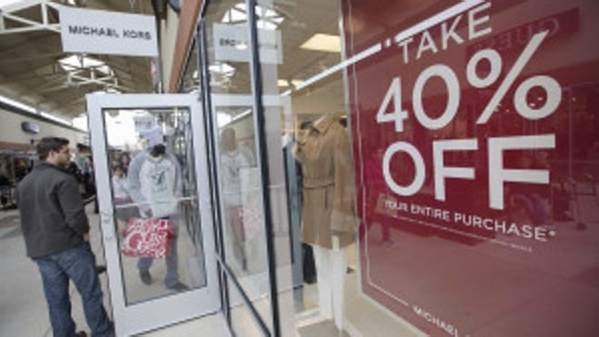 FILE - In this Nov. 27, 2015 file photo, a doorman holds the door for a shopper at a Michael Kors store at the Cincinnati Premium Outlets in Monroe, Ohio. For those willing to wait, there’s a best time of year to buy all kinds of things, from TVs to bathing suits. (AP Photo/John Minchillo, File)