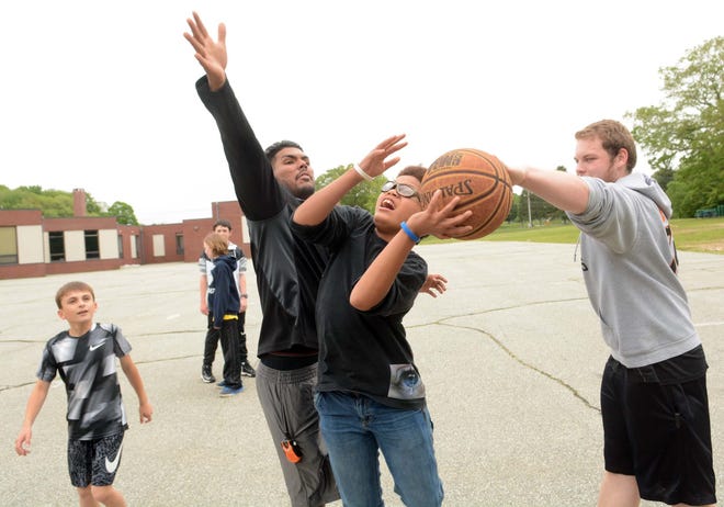 Kanye McClellan, a seventh grade Tyl Middle School student, tries to shoot between program assistant Axel DeJesus, left, and youth counselor Brendan Rothholz Wednesday at the Montville Youth Center. At far left is sixth-grader Anthony Martin. [John Shishmanian/ NorwichBulletin.com]