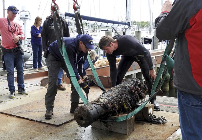 Naval History and Heritage Command underwater archaeologist George Schwarz, right, and Explosive Ordnance Disposal Technician Senior Chief Mark Faloon inspect the 200-year-old cannon on May 24, after it was recover from waters off the coast of Rhode Island and taken to Dodson Boat Yard in Stonington, Conn. [U.S. Navy via AP / NHHC underwater archaeologist Heather G. Brown]