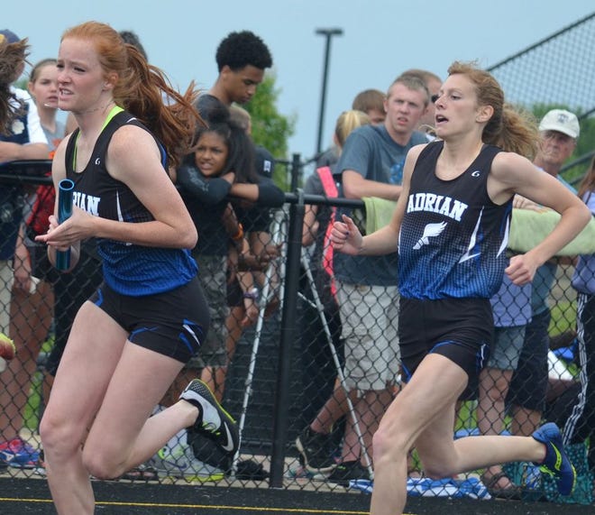 Adrian's Ryleigh Jacobs, right, takes the baton from Lauren Francoeur during the Division 2 4x200 final Saturday.