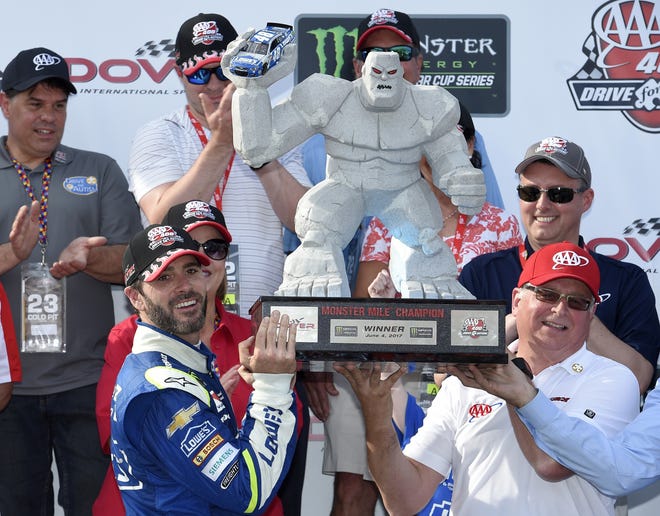 Jimmie Johnson, left, poses with the trophy Sunday in Victory Lane after he won a NASCAR Cup race at Dover International Speedway in Dover, Del. It was his 11th victory at the track. [THE ASSOCIATED PRESS]