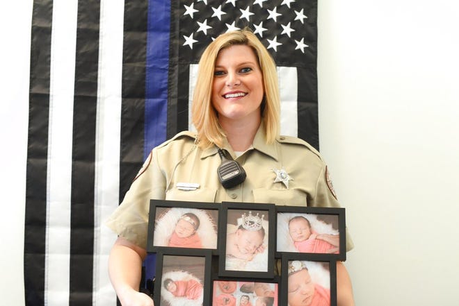 This photo taken May 12, 2017, shows Lenoir County Sheriff Deputy and school resource officer, Karen Lee holding photos of her daughter as she stands inside her at Frink Middle School in La Grange, N.C. (Janet S. Carter /Daily Free Press via AP)