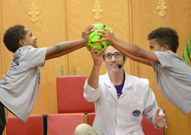 Alex O'Zone from Mad Science of Central Florida enlists the help of two volunteers to demonstrate how balance and force work together at the Tavares Civic Center on Monday. [AMBER RICCINTO / DAILY COMMERCIAL]