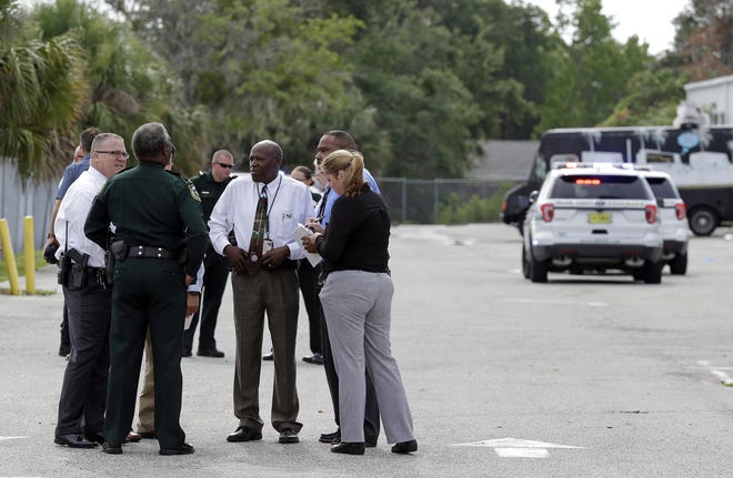 Authorities confer near the scene of a shooting where they said there were multiple fatalities in an industrial area near Orlando, Fla., Monday, June 5, 2017. The Orange County Sheriff's Office said on its official Twitter account that the situation has been contained. THE ASSOCIATED PRESS
