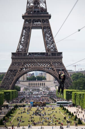 A woman rides a zip line from the second floor of the Eiffel Tower, 115 meters above the ground and 800 meters long, as part of a free event in Paris, France, Sunday, June 4, 2017. (AP Photo/Kamil Zihnioglu)