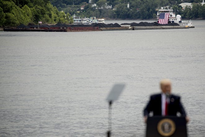 A coal barge is visible behind President Donald Trump as he speaks about infrastructure at Rivertowne Marina in Cincinnati, Ohio, Wednesday, June 7, 2017. THE ASSOCIATED PRESS