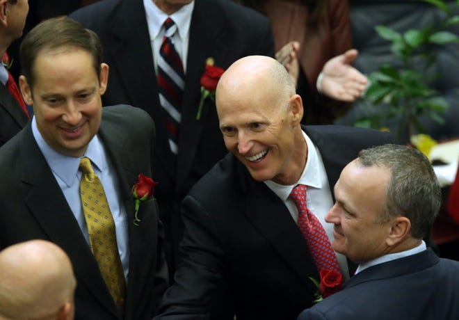 Florida Gov. Rick Scott — flanked by Sen. Joe Negron, R-Stuart, left, and Rep. Richard Corcoran, R-Land O'Lakes — makes his way to the podium to deliver his State of the State address in 2016. [AP Photo/Steve Cannon]