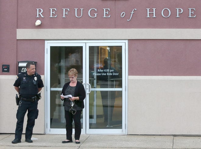 Canton police officer Tim Marks, and Jo Ann Carpenter, director of development at Refuge of Hope, stand outside the men's homeless selter before Carpenter read a statement to reporters after an officer involved shooting inside the building in Canton on Tuesday, June 6, 2017. (CantonRep.com / Scott Heckel)