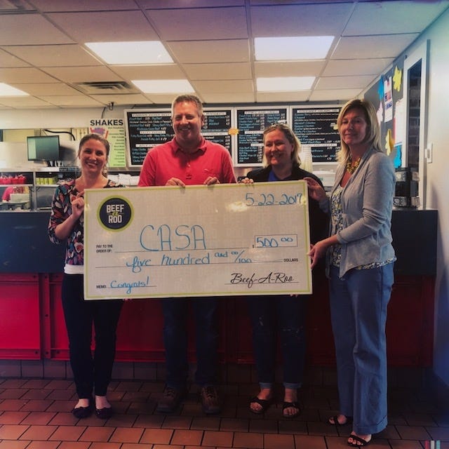 Nick Debruler, co-owner of Beef-a-Roo, gives a $500 donation to Taryn Marko, CASA program director; Leslie Erickson, treasurer of the CASA board of directors; and Audrey Engelbrecht, chair of the CASA board of directors. [PHOTO PROVIDED]