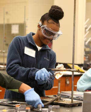 Shequasia Threatt, 16, a rising junior at Hillcrest, lights a bunsen burner as she participates in the CollegeFirst advanced placement chemistry lab held at the University of Alabama on Wednesday. Students worked with UA college mentors as they measured copper sulfate and magnesium sulfate solids and heated and separated the solid from water to find the molar mass of each solid. [Staff Photo/Erin Nelson]