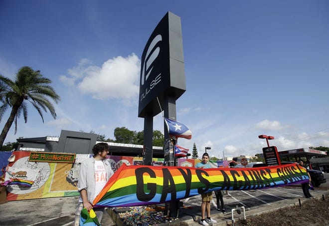 Activists hold a banner in front of the Pulse nightclub site after a news conference, Thursday, May 4, 2017, in Orlando, Fla. The owner of the Pulse nightclub said the site will become a memorial and a museum to honor the 49 people who were killed and the dozens more who were injured during the worst mass shooting in modern U.S. history. THE ASSOCIATED PRESS