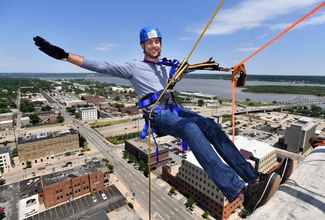 RON JOHNSON/JOURNAL STAR Journal Star Reporter Matt Buedel pauses before descending during a rappelling demonstration from the roof of the Chase Bank building in downtown Peoria by the Over the Edge Peoria team for media members on Friday.