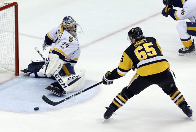 Pittsburgh's Ron Hainsey (65) pokes the puck past Nashville goalie Juuse Saros in the second period of the Penguins' 6-0 victory in Game 5 of the Stanley Cup Final. [Gene J. Puskar/The Associated Press]