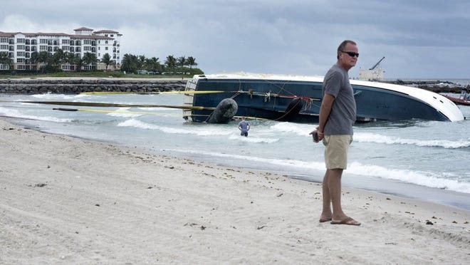 Yacht owner Thomas Baker stands on the beach last fall as the salvage company employees work on towing his yacht ashore. Melanie Bell / Daily News