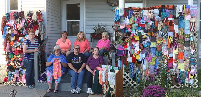Laura Gray, (standing left) and (seated, back row, left to right) Darla Ankeny, Hazel Daily, Toni Kaltenbaugh (seated, front row left to right) Tami Stone, Julie Deibel, and Linda Bennington with the scarves that will be donated. (TimesReporter.com / Jim Cummings)