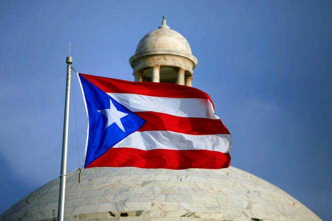The Puerto Rican flag flies in front of Puerto Rico's Capitol in San Juan, Puerto Rico. Puerto Rico's governor is pushing ahead with his top campaign promise of trying to convert the U.S. territory into a state, holding a June 11 referendum to let voters send a message to Congress.