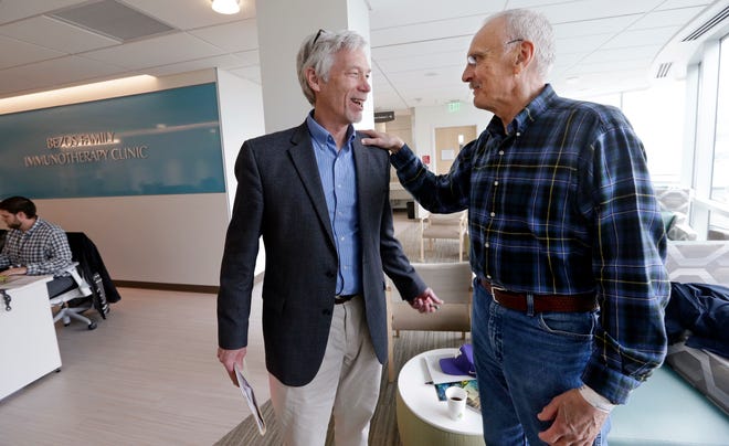 In this photo taken March 29, 2017, Dr. David Maloney of the Fred Hutchinson Cancer Research Center is greeted by patient Ken Shefveland, whose lymphoma was successfully treated with CAR-T cell therapy. Immune therapy is the hottest trend in cancer care and its next frontier is creating "living drugs" that grow inside the body into an army that seeks and destroys tumors.  (AP Photo/Elaine Thompson)