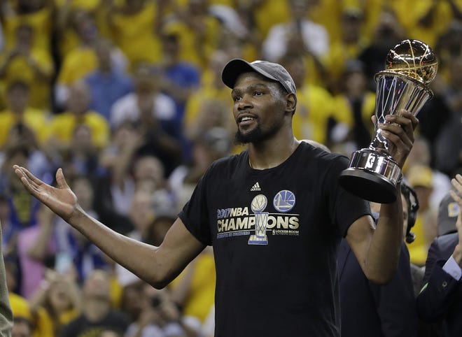Golden State Warriors forward Kevin Durant gestures as he holds the Bill Russell NBA Finals Most Valuable Player Award after Game 5 of basketball's NBA Finals between the Warriors and the Cleveland Cavaliers in Oakland, Calif., Monday, June 12, 2017. The Warriors won 129-120 to win the NBA championship. (AP Photo/Marcio Jose Sanchez)