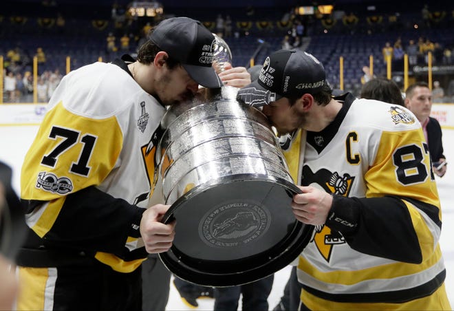 Pittsburgh Penguins' Evgeni Malkin (71), of Russia, and Sidney Crosby (87) kiss the Stanley Cup after defeating the Nashville Predators 2-0 in Game 6 of the NHL hockey Stanley Cup Final, Sunday, June 11, 2017, in Nashville, Tenn. (AP Photo/Mark Humphrey)