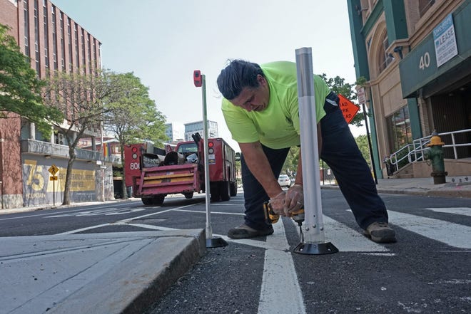 Steven Fonseca, a city employee, attaches a marker to separate the bicycle lane from parking spots. [The Providence Journal/Sandor Bodo]