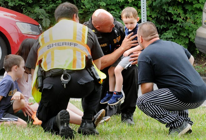 (File) Deputy Sheriff Keith Clymer from the Bucks County Sheriff's Department comforts children at an accident scene on the corner of Edison-Furlong Road and state Route 611 in Doylestown Township on Wednesday, July 13, 2016. Clymer, while off-duty, was killed Tuesday, May 16, 2017, when his motorcycle collided with a truck that turned into his path on state Route 313 in East Rockhill, police said.