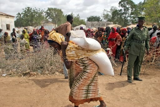 A woman carries sacks of food aid at a refugee camp in Somalia. [AP Photo/Khalil Senosi]