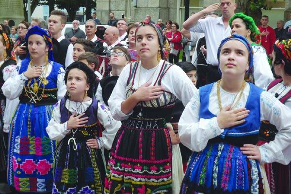 Membros do grupo folclórico da Discovery Language Academy escutam o hino nacional durante a cerimónia do içar da Bandeira Portuguesa junto à Câmara Municipal de New Bedford para assinalar o Dia de Portugal.