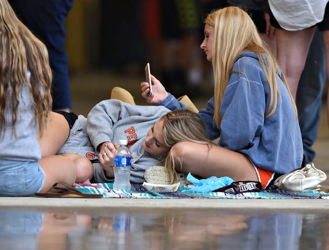 Pennsbury students Sydney Pender (left), 16, and Ava Pollazzi, 16, both of Lower Makefield, pass the time during a rain delay Friday, June 16, 2017, before the start of the PIAA 6A baseball final at Penn State University.