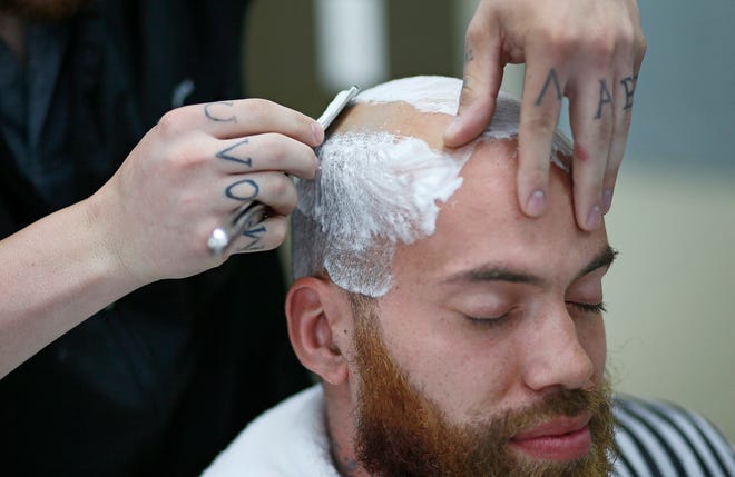 Derrick Hawthorne, 28, of the North Side receives a straight razor head shave. Hawthorne first started going bald after shaving his head when he was 18, and it never grew back as thick. [Adam Cairns/The Columbus Dispatch]