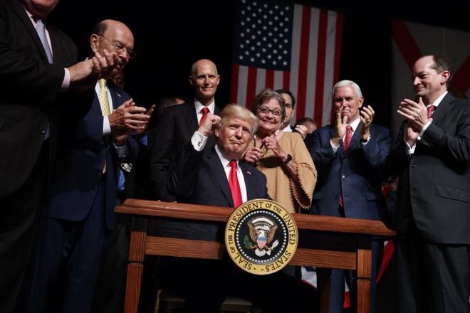 President Donald Trump pumps his fist after signing an executive order on Cuba policy, Friday, June 16, 2017, in Miami. From left are, Commerce Secretary Wilbur Ross, Florida Gov. Rick Scott, Cary Roque, Vice President Mike Pence and Labor Secretary Alex Acosta. (AP Photo/Evan Vucci)