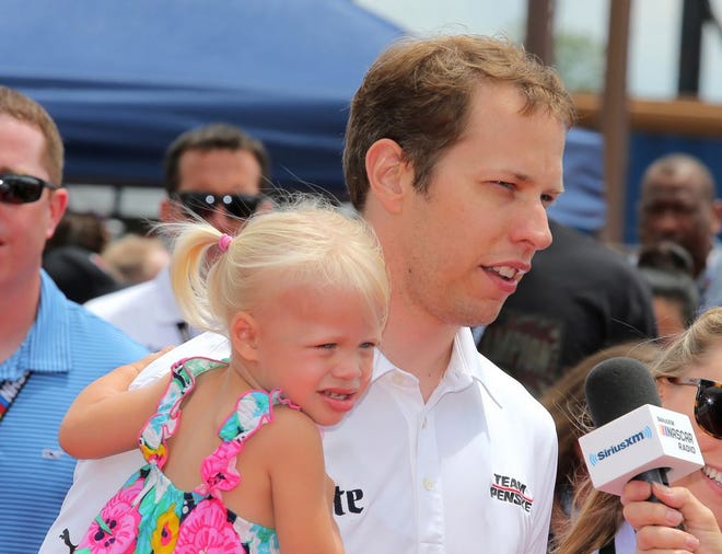 NASCAR driver Brad Keselowski holds his daughter, Scarlett, while being interviewed before Sunday's race at Michigan International Speedway.