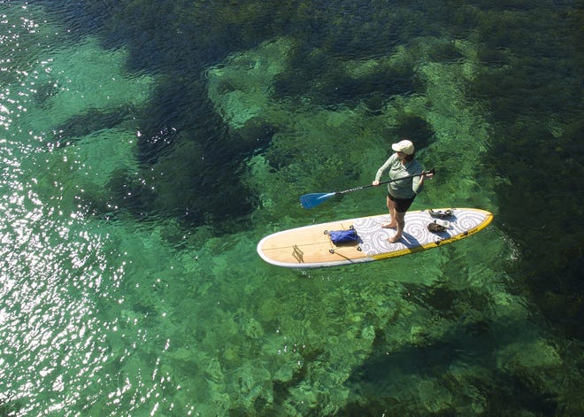 A paddle-boarder floats along the Rainbow River. While the public debates minimum flows and levels, water officials say the springs' problems go beyond that and need our focus. [Doug Engle/Ocala Star-Banner]