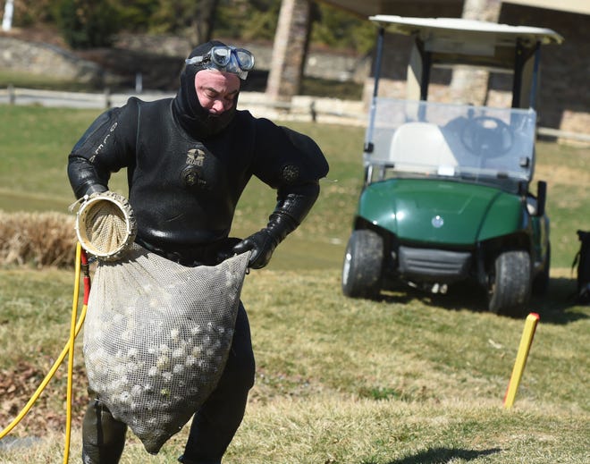 Steve Goodley carries a bag of 1,000 golf balls out of the pond at Heritage Hill Golf Resort on Feb 23. Goodley, a former amateur golfer, now makes a full-time living diving for lost golf balls year round.