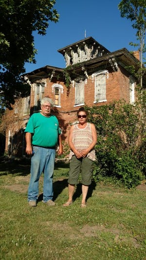 Havana residents Rick and Connie Clifton stand in front of a mansion which is located on the grounds of their Havana Hops business in Bath. The couple are growing hops for craft breweries and have a buyer for their first harvest. They expect to expand operations next year. In the future, the mansion will be renovated and serve as a wedding and event venue where they can also serve craft beer.