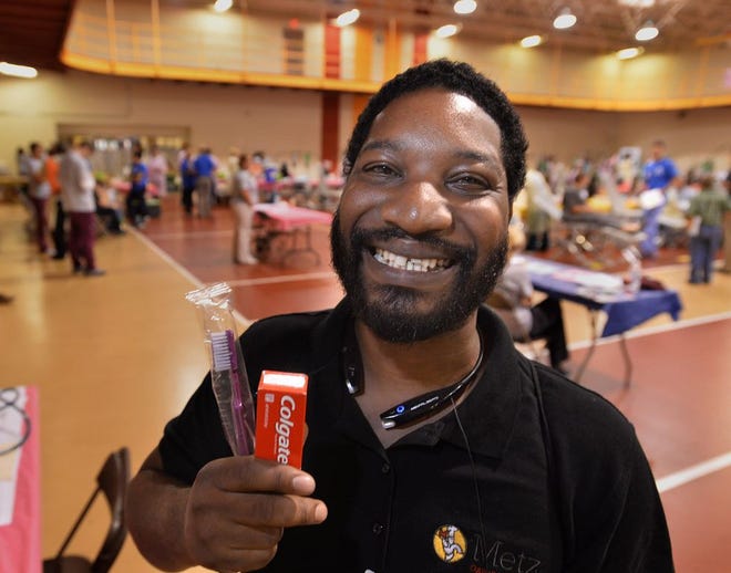 Tony McLendon II, 32, smiles and shows off his new toothbrush and toothpaste on June 16, the first day of a free two-day dental held at the Gannon University Recreation and Wellness Center in Erie. McLendon, of Erie, received a dental cleaning. The clinic, organized by Mission of Mercy, is providing free examinations, x-rays, fillings, root canals and other dental care at no cost regardless of the patientâ€™s income or where they live. More than 400 people are volunteering at the clinic, including local and out-of-town dentists, dental hygienists, oral surgeons. [CHRISTOPHER MILLETTE/ERIE TIMES-NEWS]