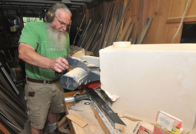 Ken Davis, owner of East Street Art, cuts moldings to make a frame in his Mansfield shop.