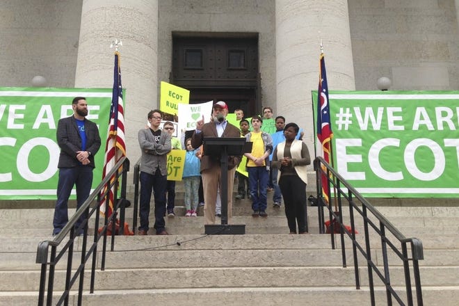 Bill Lager, center in cap, founder of Ohio's largest online charter school, the Electronic Classroom of Tomorrow or ECOT, speaks to hundreds of supporters during a Tuesday, May 9, 2017, rally outside the Statehouse in Columbus, Ohio. (AP Photo/Julie Carr Smyth)