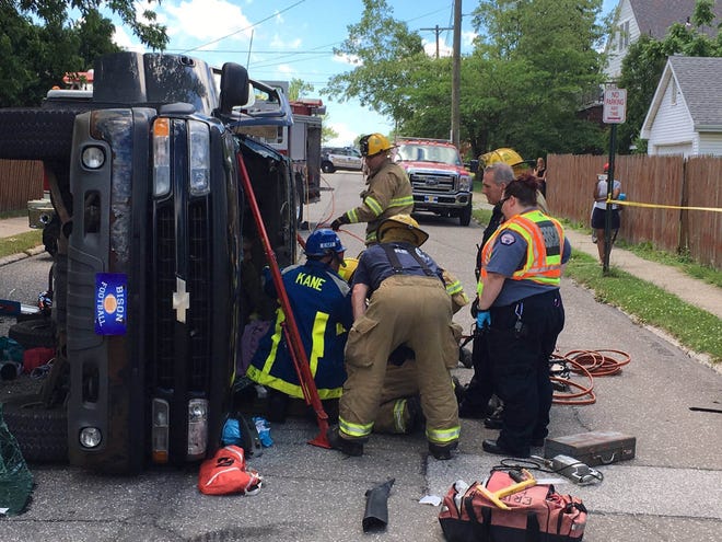 Erie firefighters work to free a woman from an SUV that flipped on its side at the intersection of West 34th and Maple streets June 20. [TIM HAHN/ERIE TIMES-NEWS]