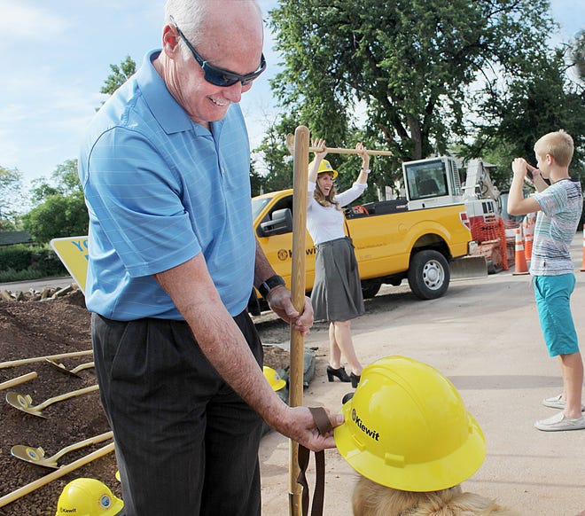 CHIEFTAIN PHOTO/TRACY HARMON Canon City Administrator Tony O'Rourke gives his dog Murphy a try with the hardhat while City Councilwoman Ashley Smith poses for a photo for her son following groundbreaking ceremonies for $3.5 million in street repairs in Canon City Tuesday.