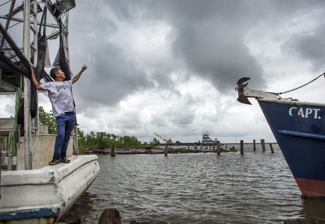Fisherman Thiet Tran said he was coming in early from Lake Borgne because of the bad weather. He looks up at the clouds while docked in Bayou Bienvenue as Tropical Storm Cindy heads toward Louisiana on Tuesday. [The Associated Press]