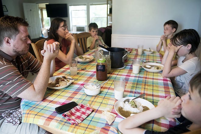 The Sell family says a prayer before a recent Sunday dinner in Omro, Wis. [LAUREN JUSTICE/THE WASHINGTON POST]