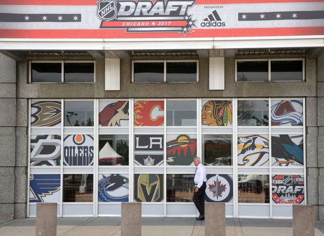 A man pass a United Center entrance with NHL team logos as preparation for the NHL Draft continue, Thursday, June 22, 2017, in Chicago. The two day draft begins Friday. (AP Photo/G-Jun Yam)