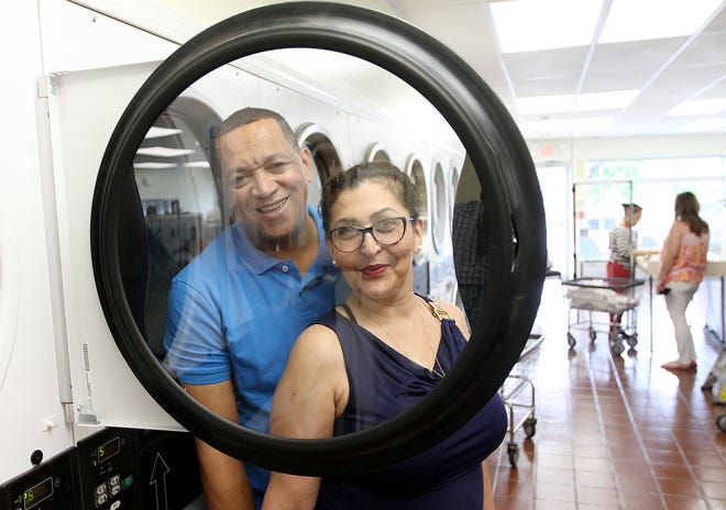 Ruben Ogando, owner of Reymond's Brother Tailor Shop, on Cranston Street in Providence, with his wife, Alba Baez, in the coin-operated laundry Ogando owns across the street. [The Providence Journal / Glenn Osmundson]