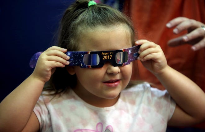 Elizabeth Rice, 4, takes a look inside solar eclipse glasses after a show inside KidSenses' traveling planetarium at Cleveland County Memorial Library on Friday. [Brittany Randolph/The Star]
