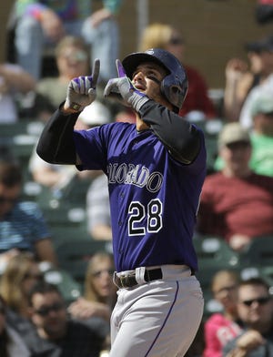 Colorado Rockies' Nolan Arenado, center, gestures skyward as he scores after hitting his second home run of the game during the fifth inning of a spring training baseball game against the Arizona Diamondbacks Tuesday, March 29, 2016, in Scottsdale, Ariz. (AP Photo/Jae C. Hong)