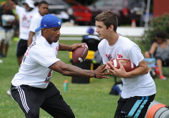 Buffalo Bills wide receiver Rod Streater (left) tries to poke the ball away from camper Gage Miller, 13, during the Streater-Moore free football camp Saturday, June 24, 2017, at Green Acres Park in Burlington.